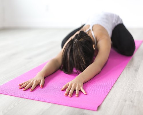 Person doing light yoga stretching indoors near a window